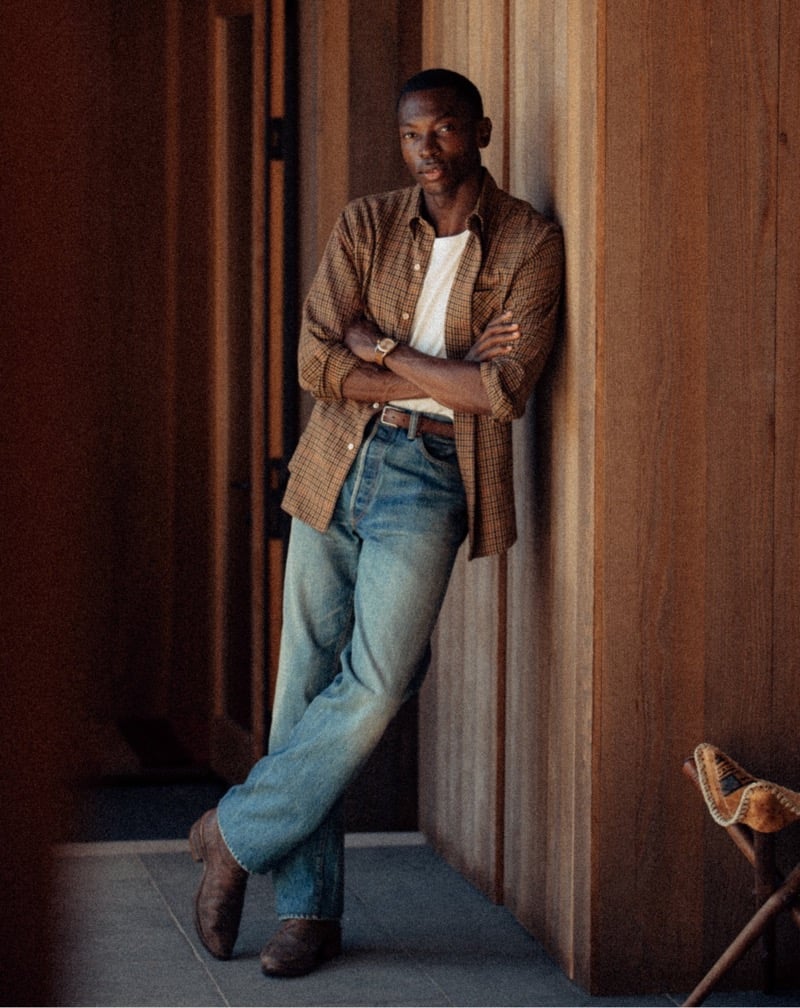 Akin Jaiye wears an open checked shirt over a white T-shirt with faded jeans.