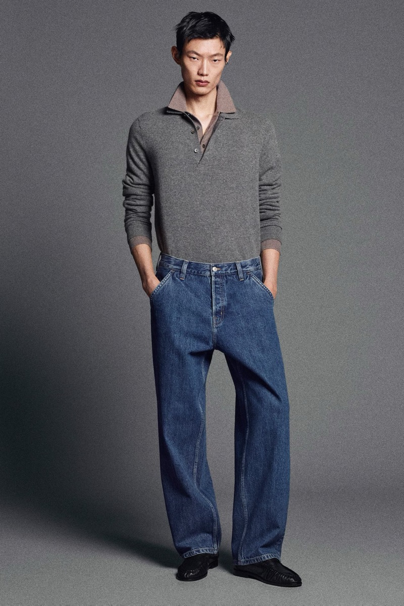 Hoyong Kim wears a gray cashmere polo tucked into wide-leg blue jeans.