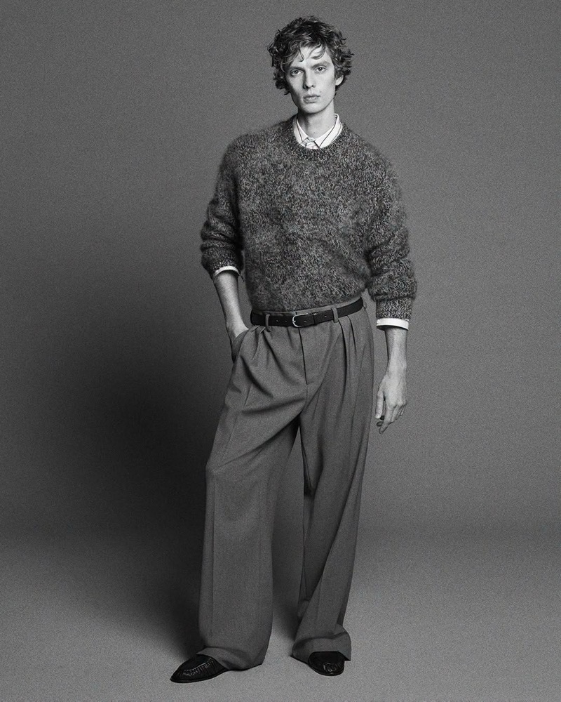 Leon Dame wears a brushed cashmere sweater with a striped shirt and wide-leg pleated trousers.