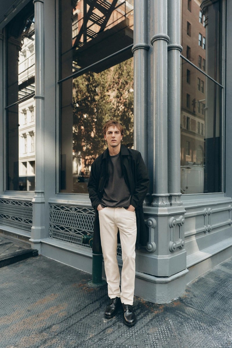 Quentin Demeester leans against a storefront in a dark overcoat and cream trousers for Massimo Dutti's fall 2026 New York edit.
