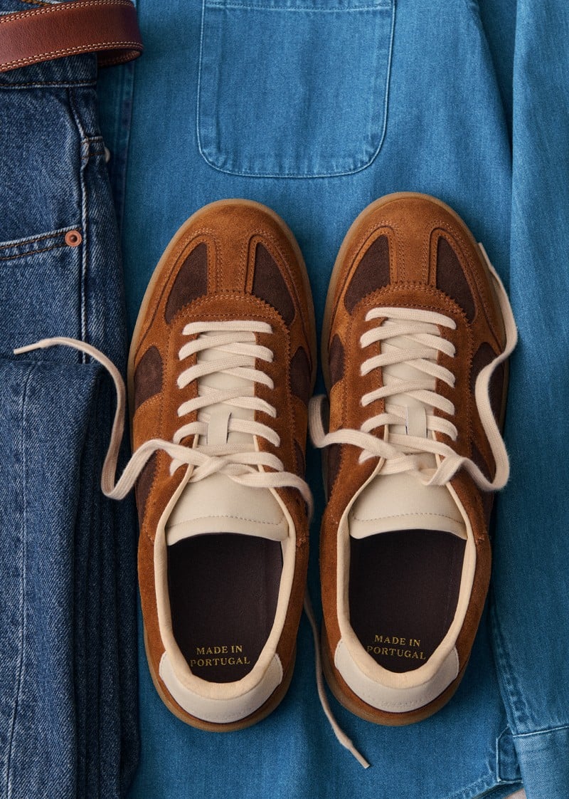 Camel and chocolate Halrin sneakers rest on blue denim.