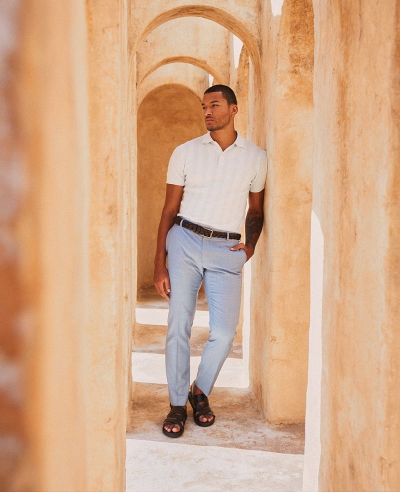 Paulo Lopes Lucio wears a white polo tucked into pale blue trousers with dark sandals.
