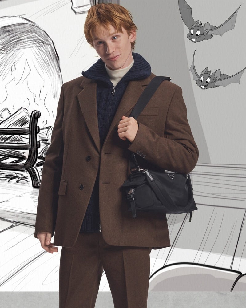 Luther Ford wears a brown suit over knitwear with a black shoulder bag behind the scenes of Prada's holiday 2026 campaign.