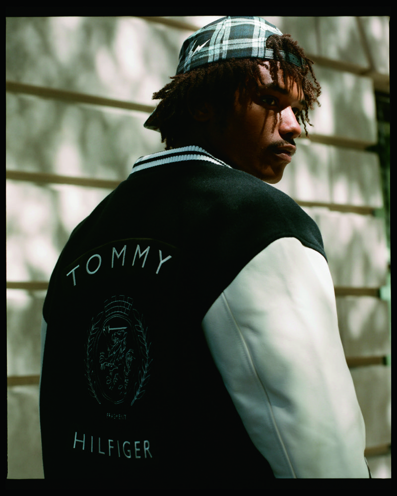 Nile Winchester looks over his shoulder in a Tommy Hilfiger varsity jacket and plaid cap.