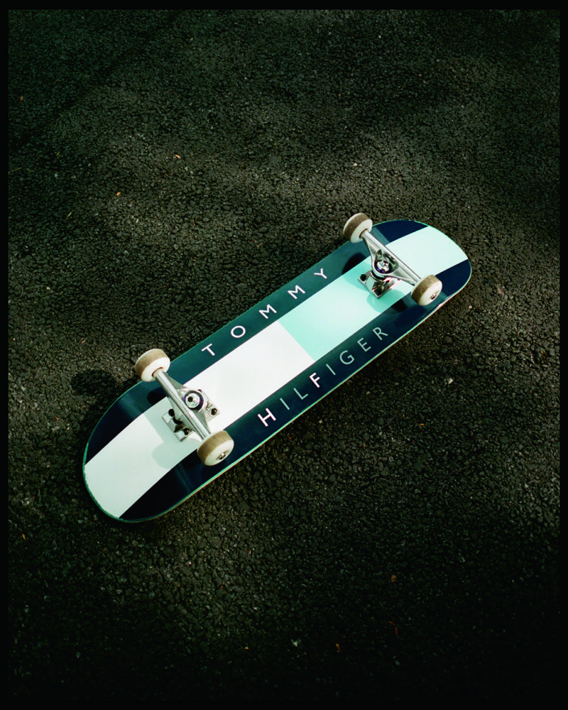 A Tommy Hilfiger x FRGMT skateboard rests on the pavement.