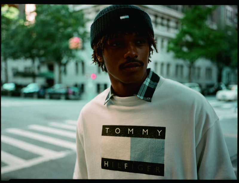 Nile Winchester wears a white logo T-shirt over a plaid shirt on a New York street.