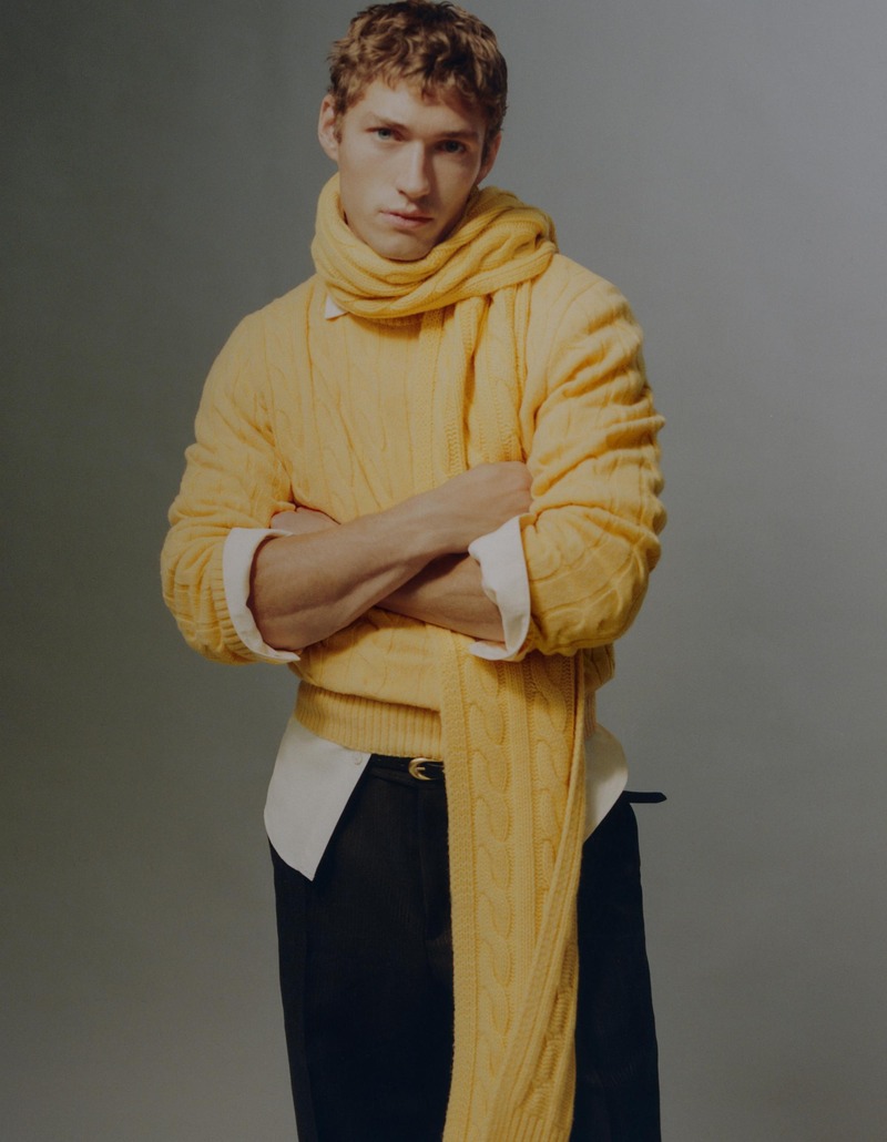 Valentin Humbroich folds his arms in a yellow cable-knit sweater and matching scarf over a white shirt.