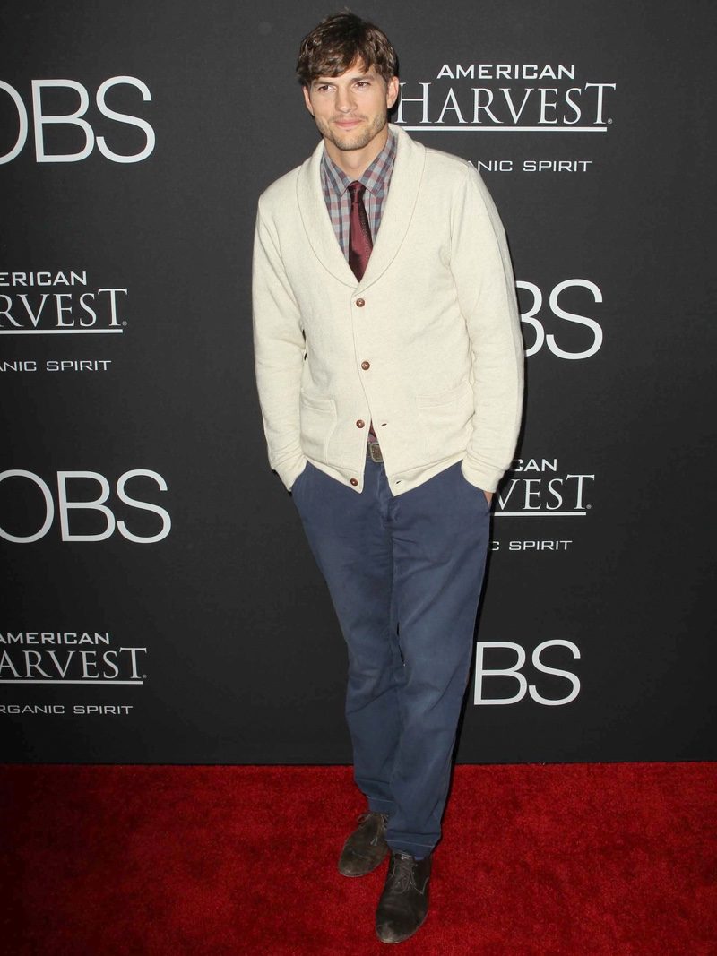 Ashton Kutcher wears a smart look with a cardigan sweater, button-down, and tie. 