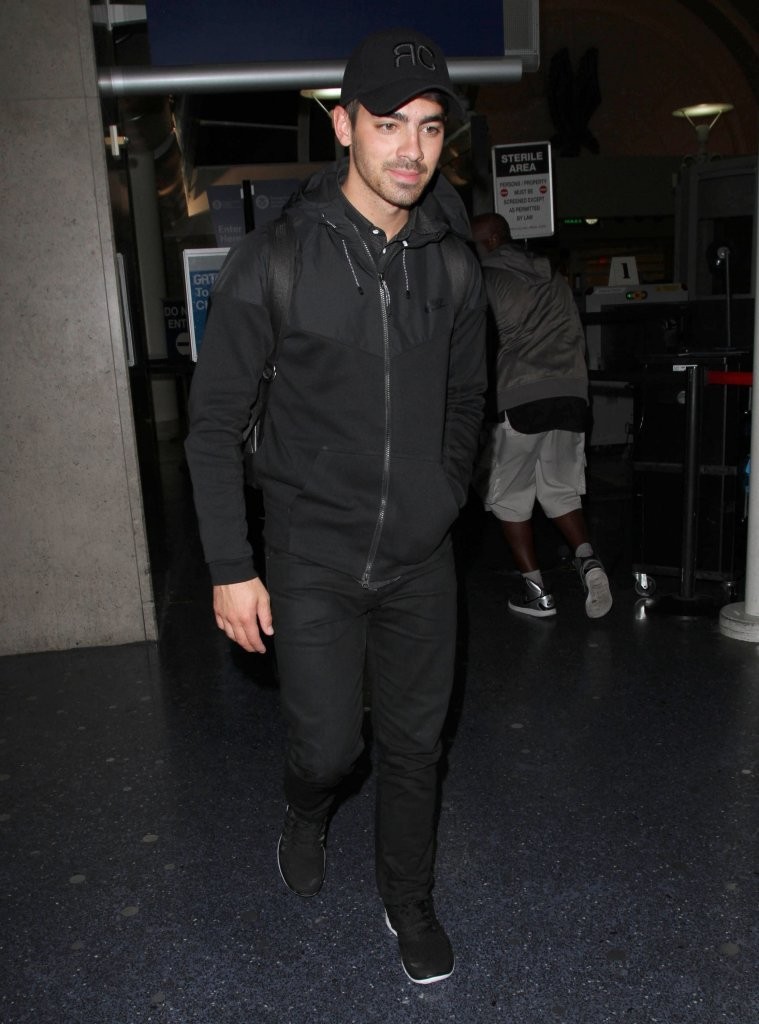 Arriving at LAX after a trip to New York, Joe Jonas was casual in a head to toe black look that included a performance jacket from NIKE on September 24, 2014.