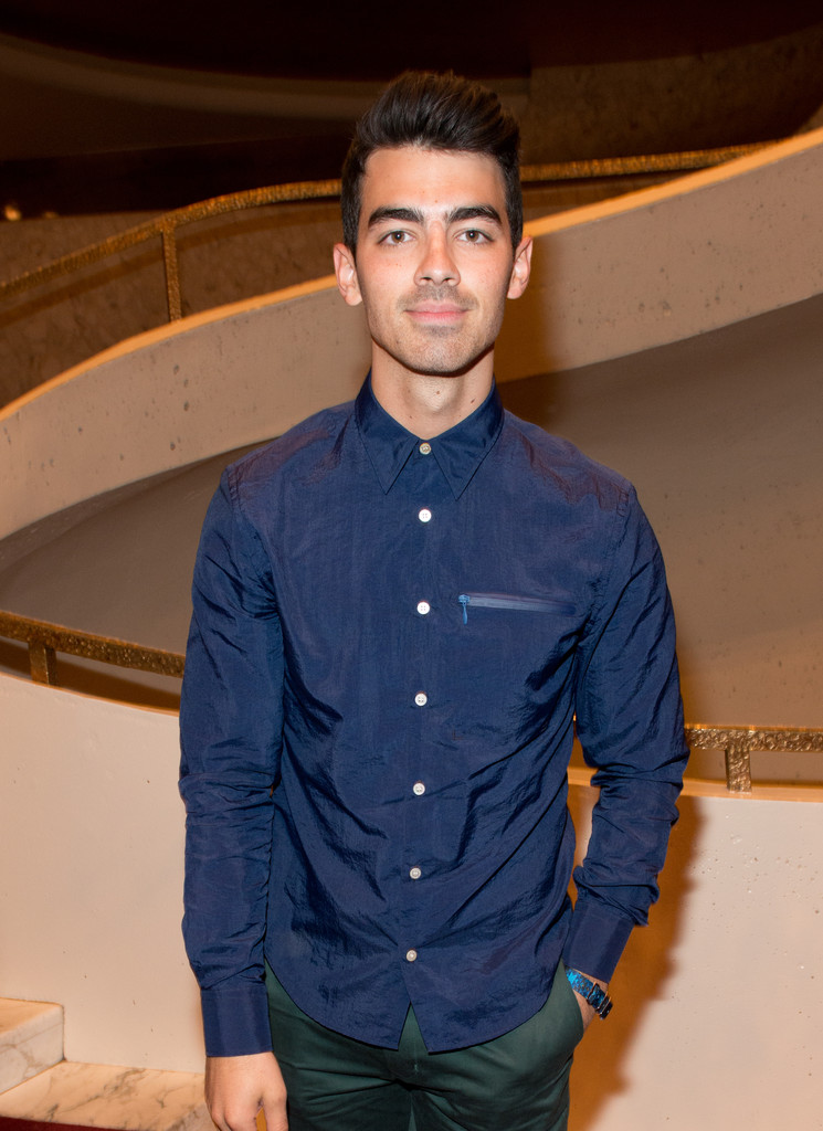 Catching Opening Ceremony's play that served as the backdrop to its runway show, Joe Jonas wears a navy blue shirt from the label.