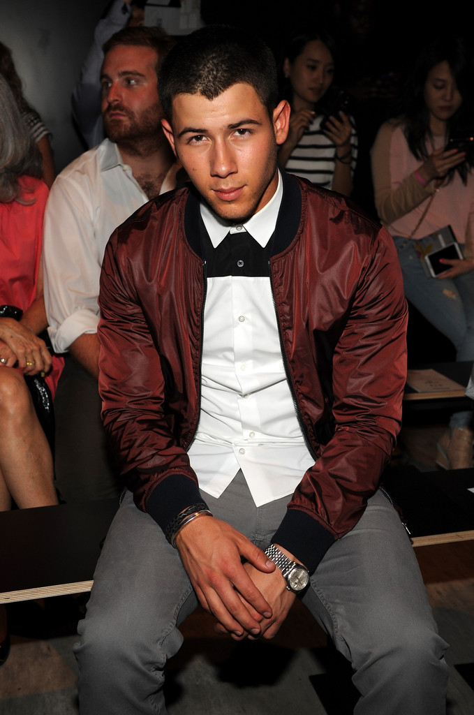 Nick wears an iridescent bomber jacket.