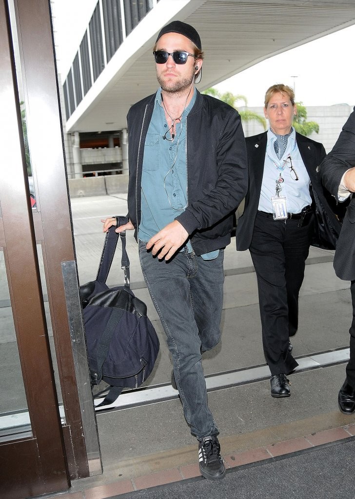 Heading out on a flight from LAX to the Toronto International Film Festival, Robert Pattinson went for a casual travel look that included the pairing of a denim shirt with a black bomber jacket.