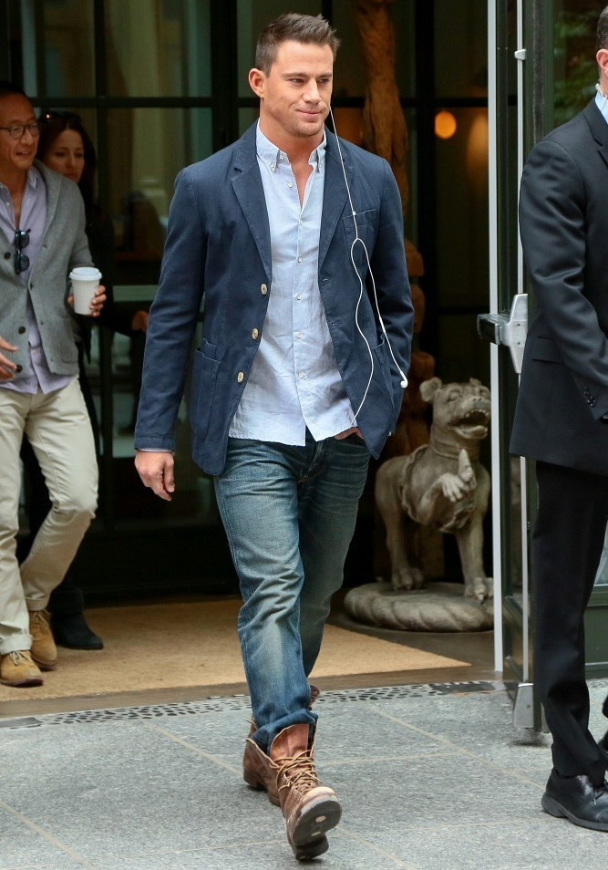 On October 10th, Channing Tatum takes a confident stroll in New York City, wearing a pair of distressed denim jeans, brown leather boots, a light blue oxford and a navy sports jacket.