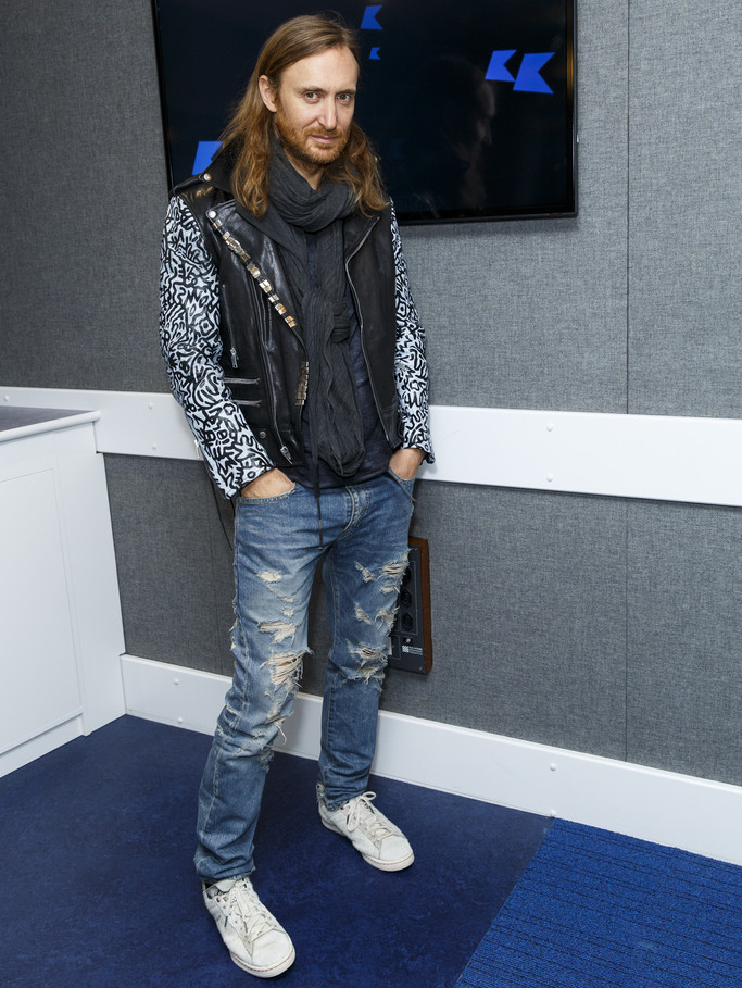 Visiting Michael & Andrea from Live @ KISS, David Guetta visited KISS FM UK studios on October 10, 2014 in London. On-trend as usual, Guetta found his style note in a Saint Laurent leather jacket, paired with ripped denim jeans and white sneakers.
