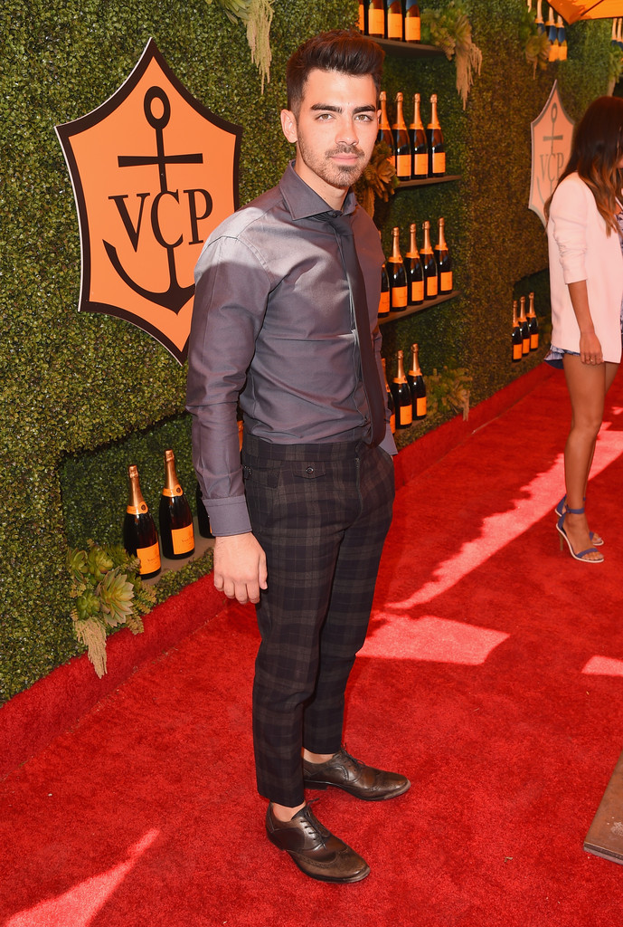 Attending the fifth annual Veuve Clicquot Polo Classic at Will Rogers State Historic Park on October 11, 2014 in Pacific Palisades, California, Joe Jonas kept his look simple with a dress shirt and tie, paired with plaid trousers and sock-less leather dress shoes.