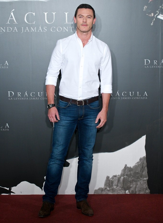 Traveling the world to promote his latest movie, 'Dracula Untold', Luke Evans was a pristine picture of style at a Madrid photocall at the Villamagna Hotel on October 21st. Evans kept it casual but chic in a pair fitted distressed denim jeans and a classic white dress shirt.