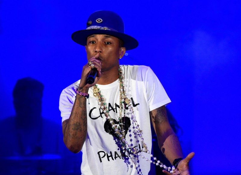 Performing, Pharrell wears a Chanel shirt and beaded jewelry.
