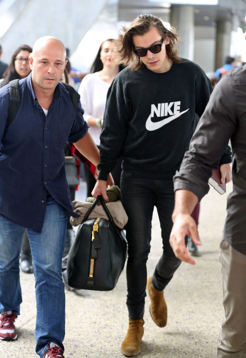 Arriving at LAX, Harry Styles kept it casual in a black NIKE logo sweatshirt, cigarette thin black denim jeans and Saint Laurent ankle boots. Styles also had in toll his Tom Ford Buckley leather bag.
