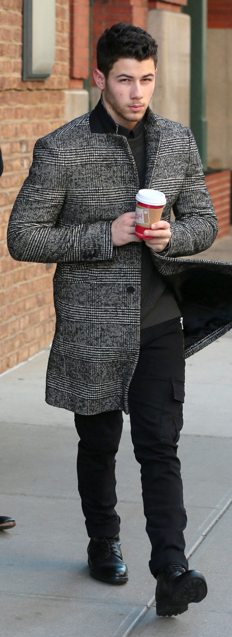 Currently promoting his self-titled album, Nick Jonas is out and about in New York City, where he was spotted on November 18th, bundling up in a coat from AMI. The tweed coat makes quite the sartorial statement with its smart black & white checks.