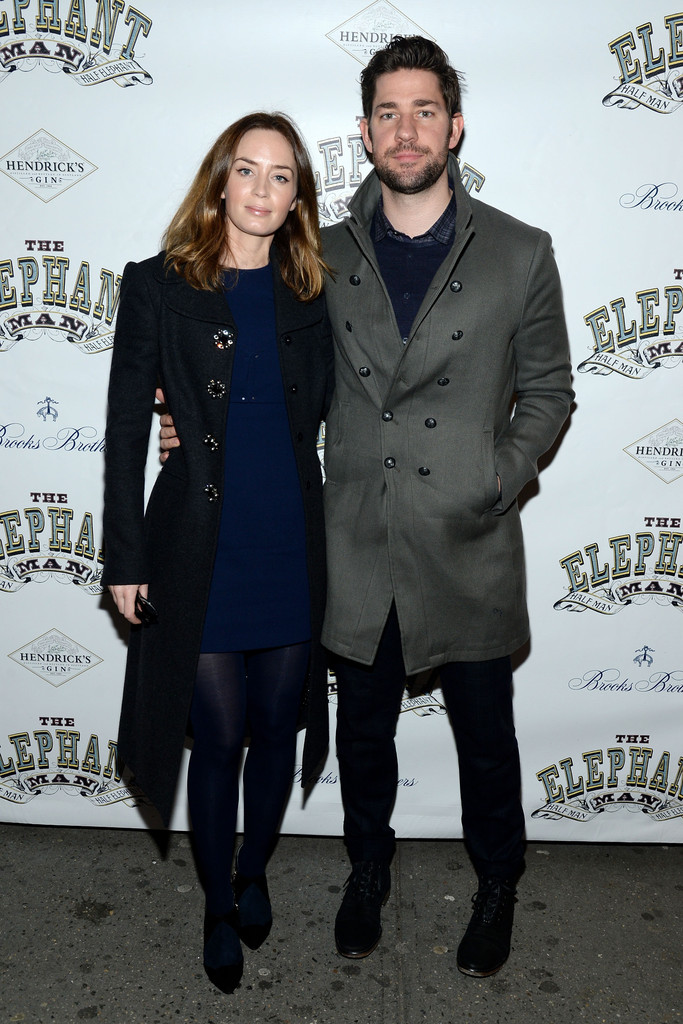 Attending the opening night of Broadway's 'Elephant Man' with his wife Emily Blunt on December 7th, actor John Krasinski stopped to pose for a photo. For the occasion, Krasinski wore a look from American designer John Varvatos, pairing one of his signature double-breasted coats with a simple jean and sweater combo.