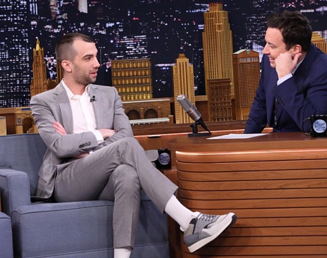 Wearing Z Zegna sneakers with a trim gray suit, actor Jay Baruchel's style is effortless as he sits down for an interview with Jimmy Fallon.