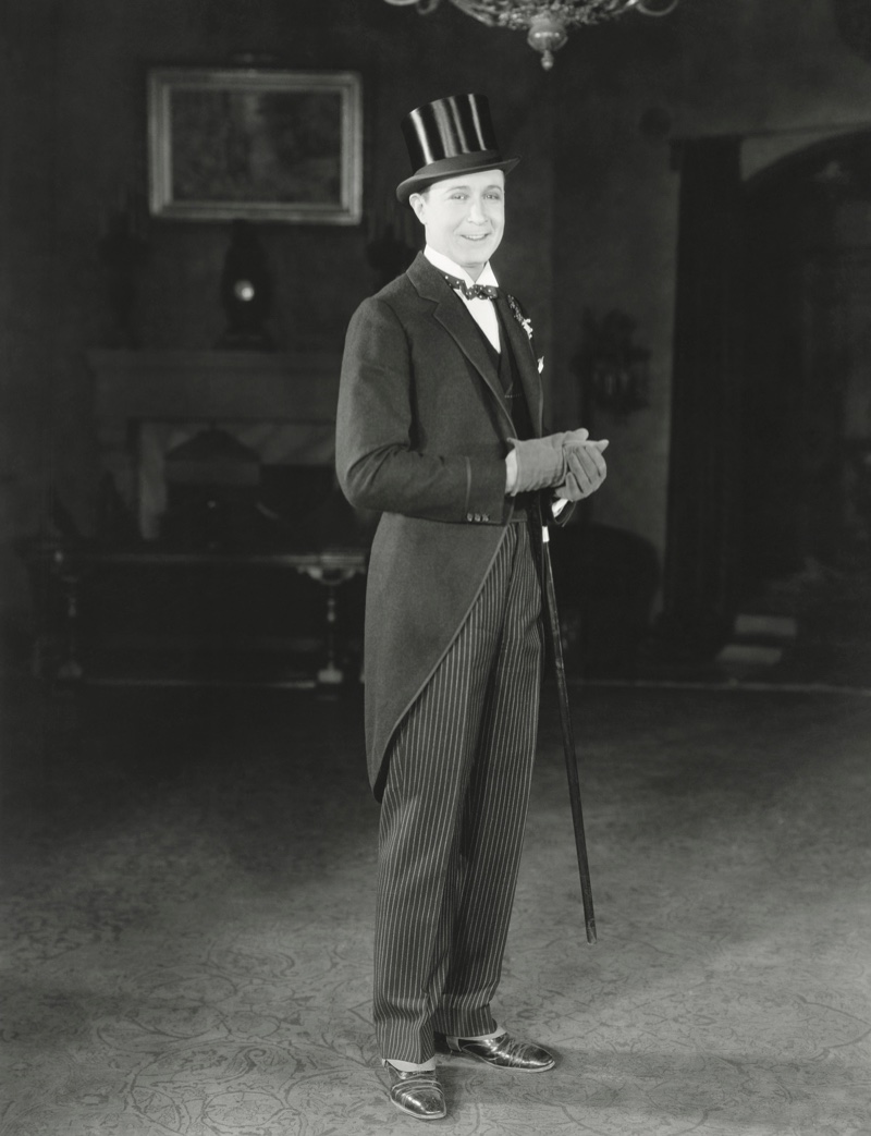 A groom on his wedding day wearing a formal morning suit look complete with a top hat and gloves. 