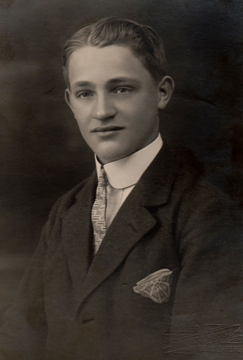 A 1920s portrait shows a man wearing slicked back hairstyle with a part.