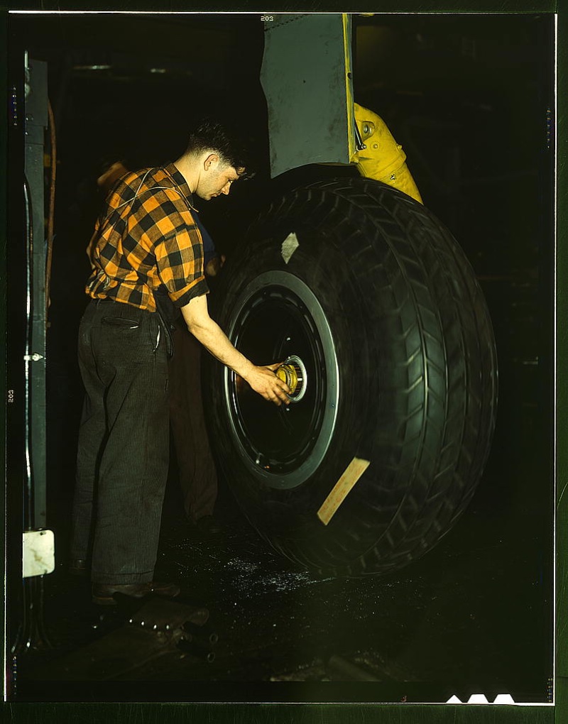 Sporting a check shirt, a worker inspects a landing wheel of the transport planes at Willow Run manufacturing plant in Michigan circa 1941-45.