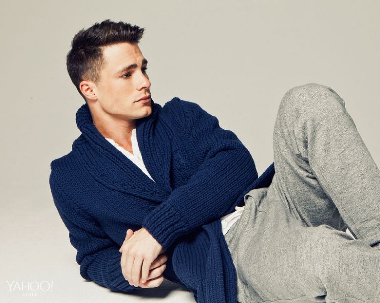 Colton Haynes lounges in a blue cardigan sweater from Michael Kors, paired with Rag & Bone henley and gray J.Crew sweatpants.