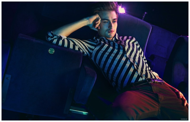 Douglas Booth poses for a relaxed photo in a striped top and leather belt from Prada.