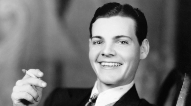 Revisiting Hairstyles for Men in the Twenties Flashing a smile, a young man in the 1920s wears a slick hairstyle featuring a side part.