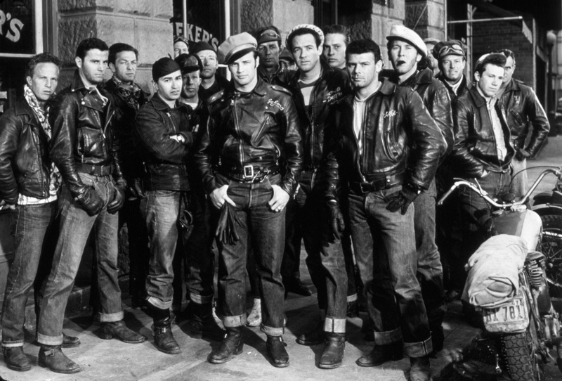 Acting legend Marlon Brando poses on set of "The Wild One" with his biker gang ensemble, perfecting the ideal rebellious look.