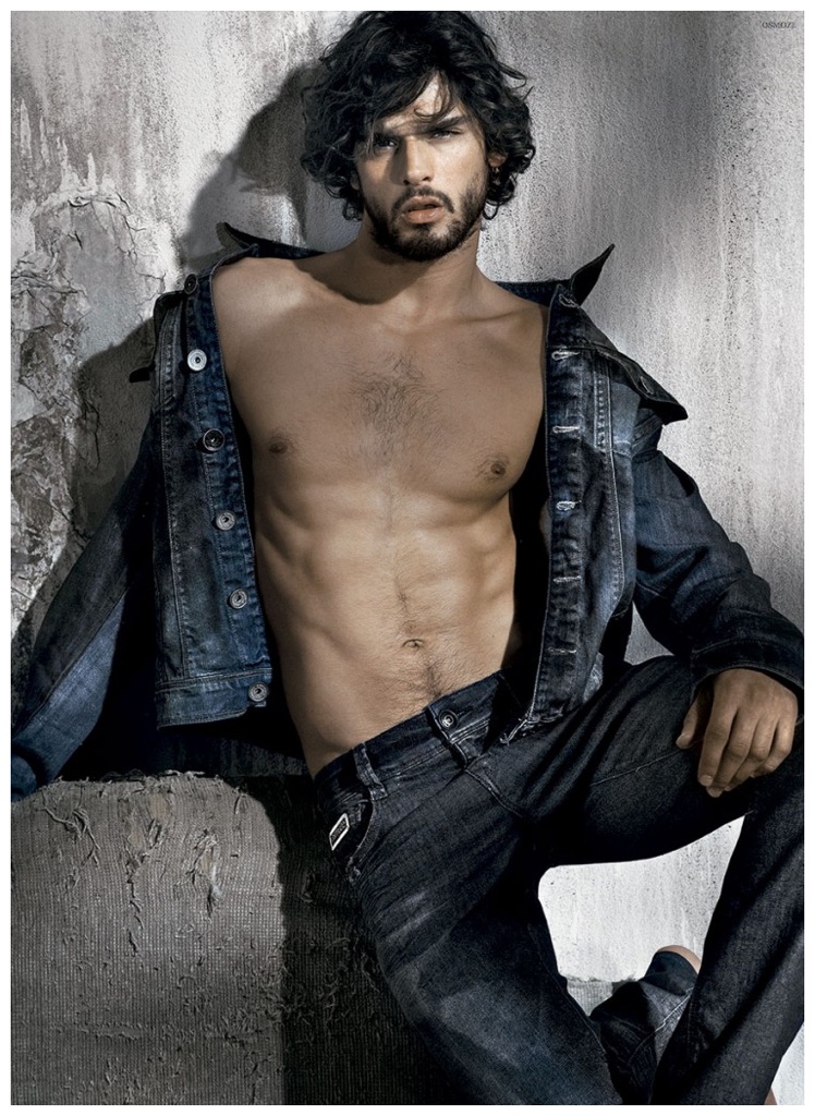 Marlon Teixeira models an open denim jacket worn over bare skin with a pair of distressed denim jeans for a double denim ensemble.