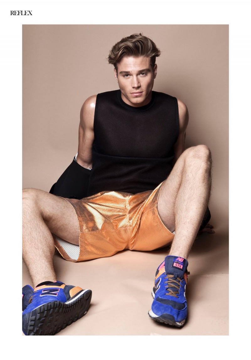 Sporting a bold active look, Matthew Noszka rocks gold shorts with sneakers and sleeveless top.