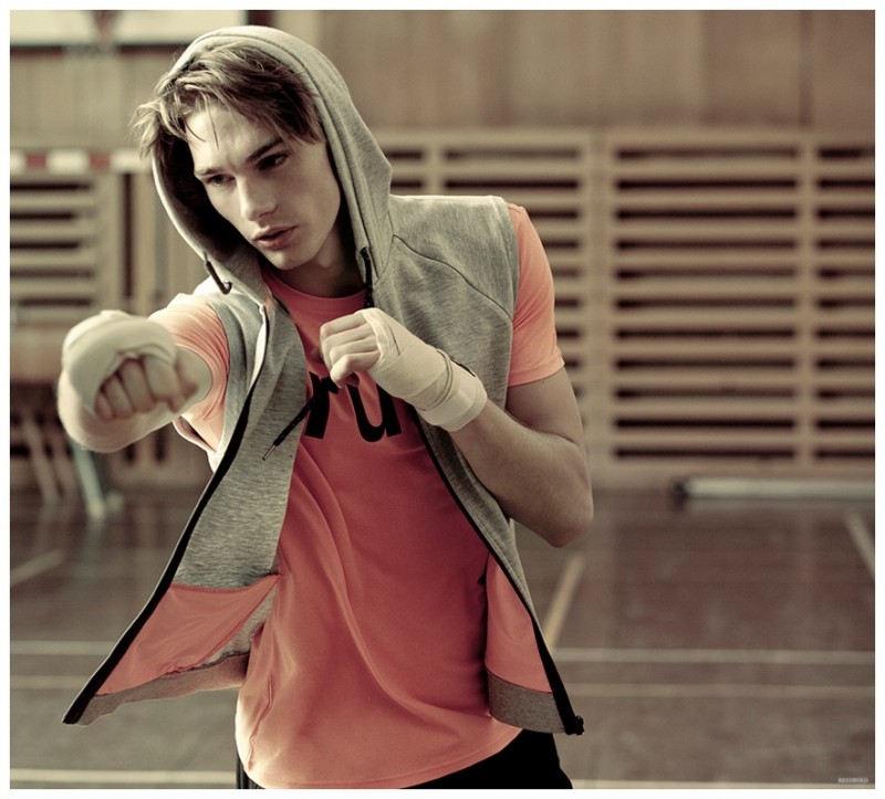 Wearing a sleeveless hoodie and a bright graphic t-shirt, Tommy Marr throws a punch.