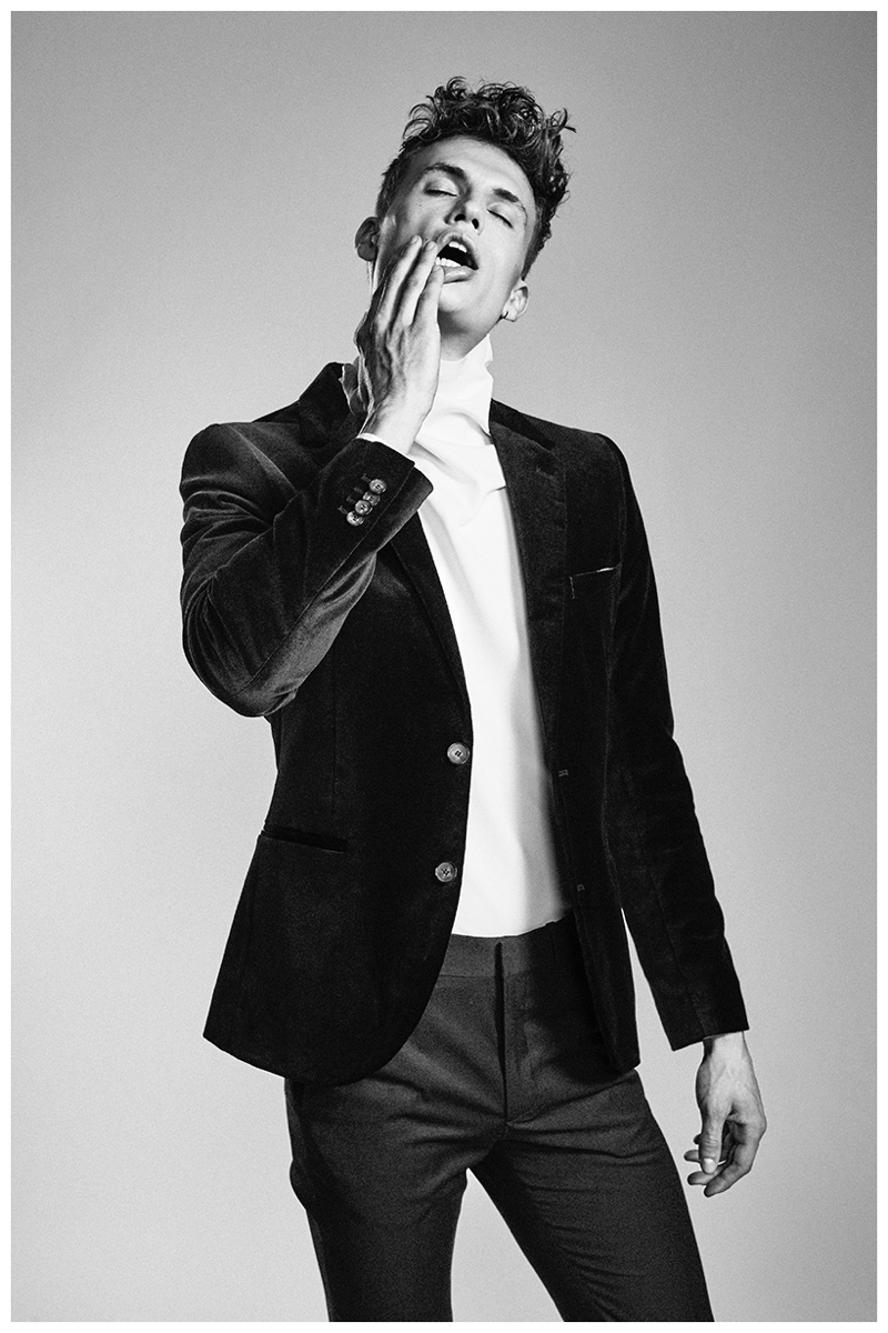 Mads is expressive in a turtleneck and blazer.