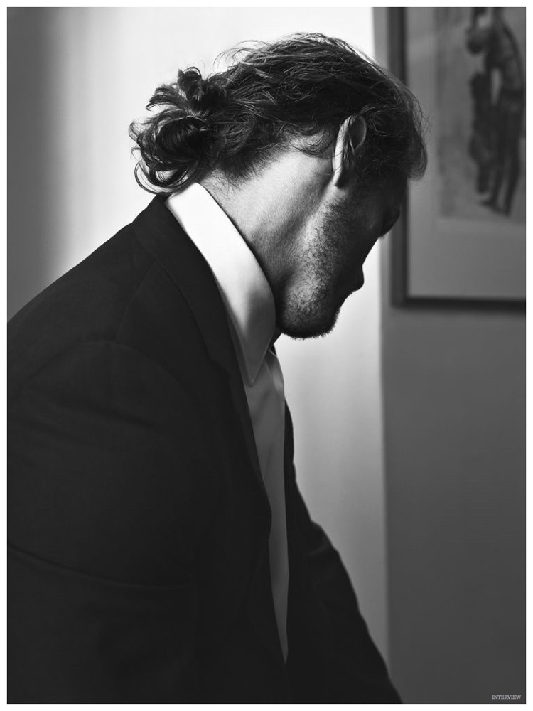 Posing for a black & white image, Sam Heughan rocks a man bun.