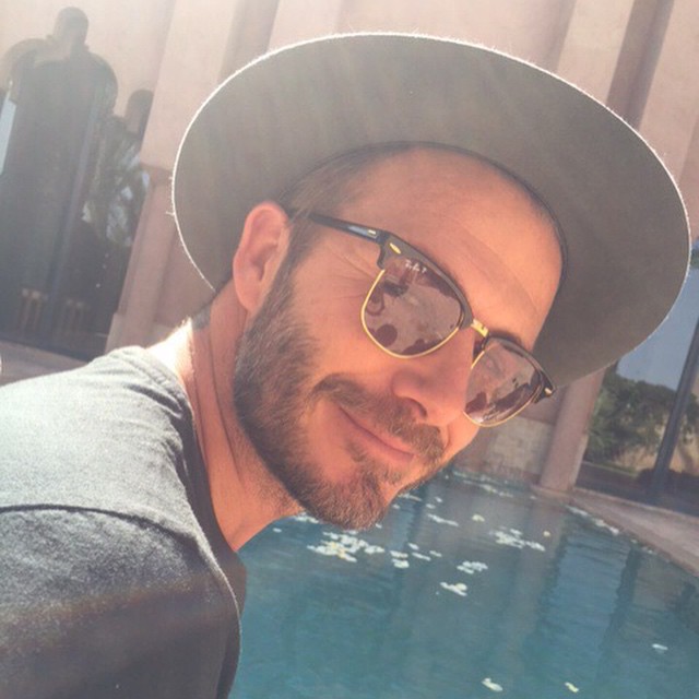 David Beckham takes in the day poolside in his Ray-Ban sunglasses.