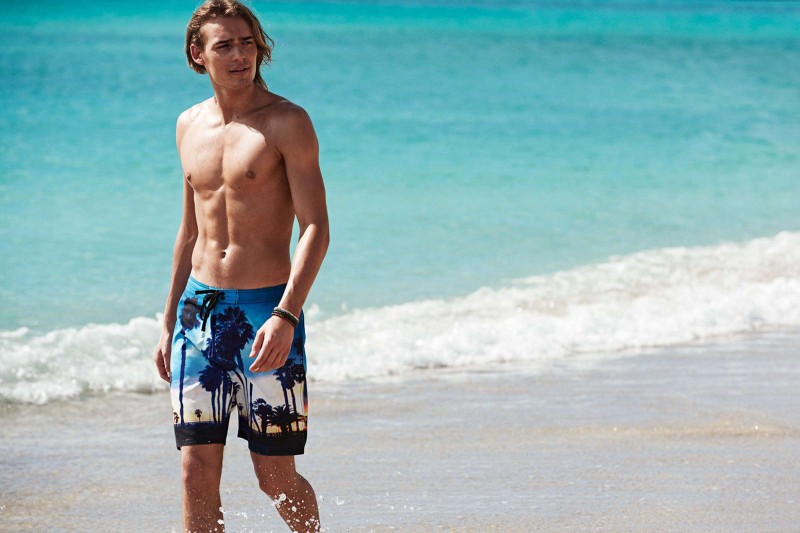 Sporting a photographic print, Ton Heukels takes a walk in H&M swimwear.