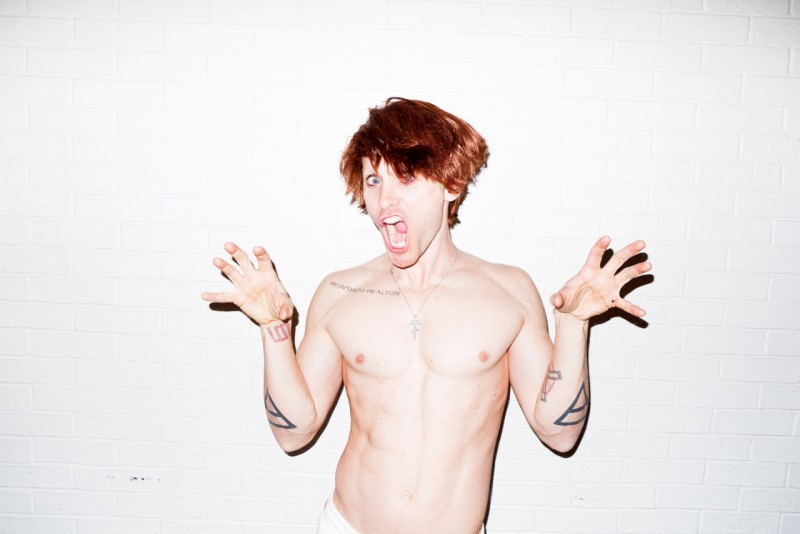 A shirtless Jared Leto poses quirky in a red wig.