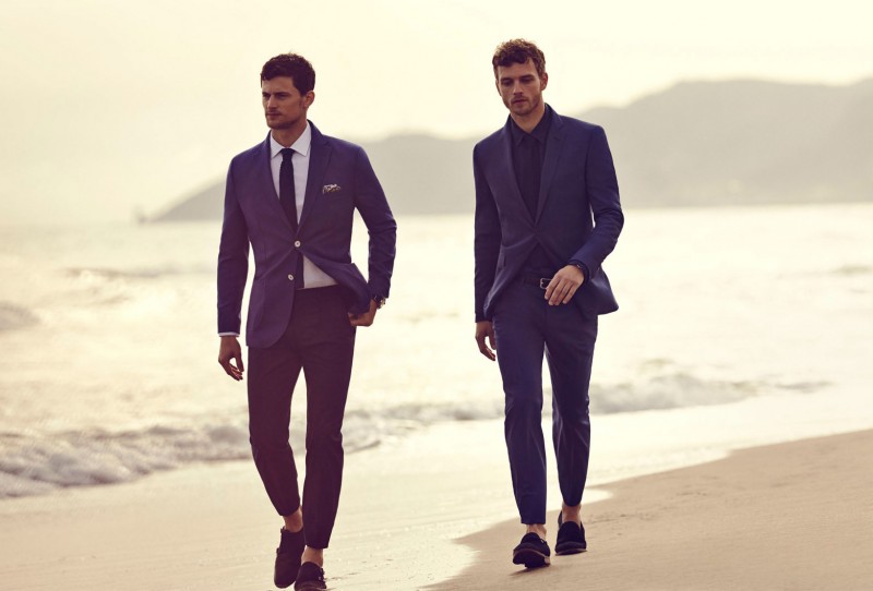 Garrett and Benjamin go for a walk on the beach in impeccably tailored suits.