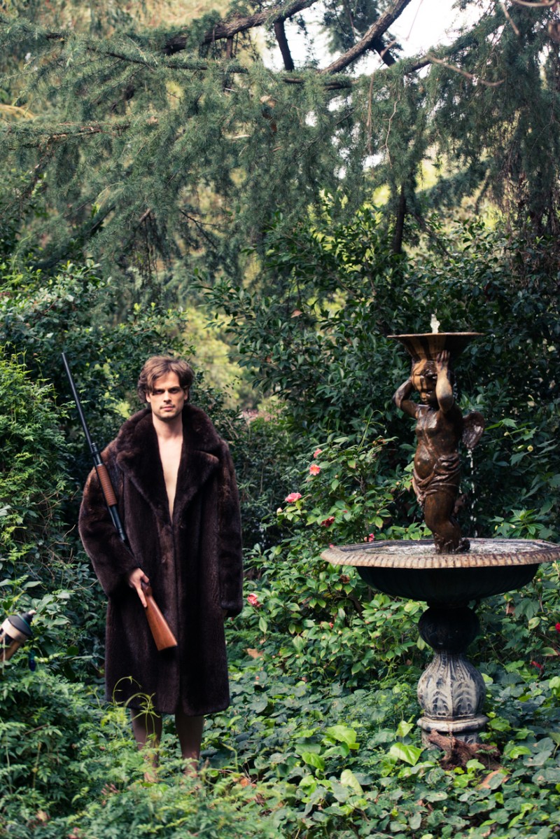 Matthew Gray Gubler poses in a vintage fur with a rifle.