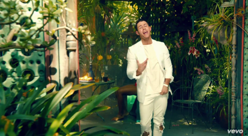 Nick Jonas channels summer in a white hot look built around denim jeans ripped at the knees.