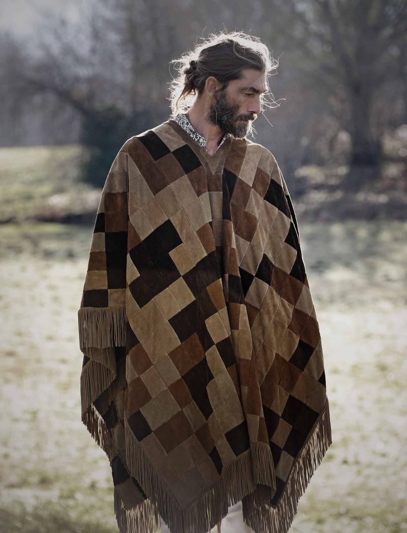 Pictured outdoors in a dramatic poncho, Patrick Petitjean rocks a trendy man bun.