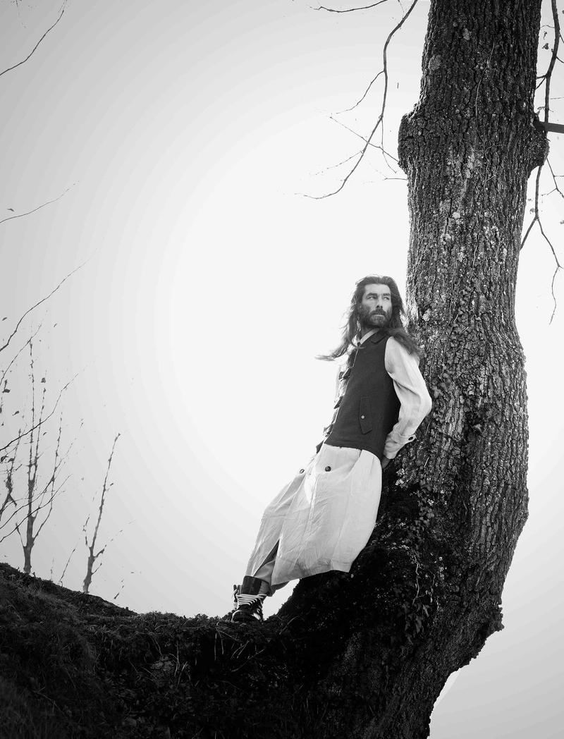 Embracing playful proportions, Patrick Petitjean poses on a high tree branch.