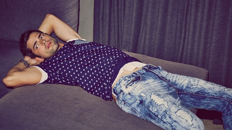 Sean O'Pry relaxes in a pair of distressed denim jeans.