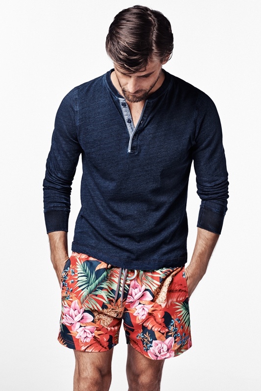 The male model wears a henley shirt with tropical print shorts