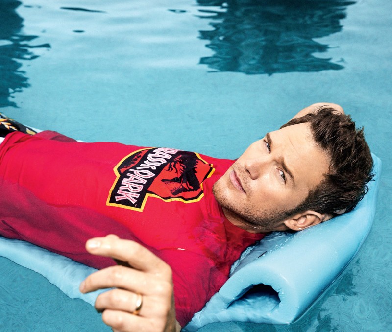 Lounging in the pool, Chris Pratt wears a red Jurassic Park logo t-shirt.