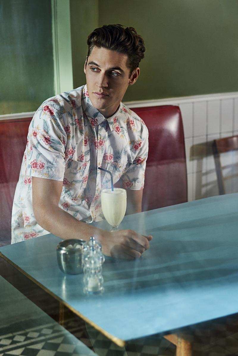 Isaac enjoys a milkshake, donning a short-sleeve printed shirt.