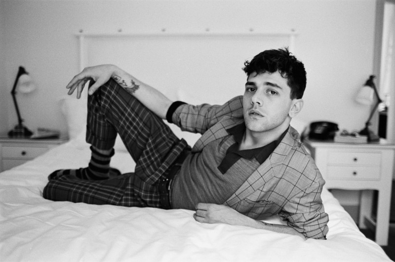 Embracing a windowpane print, Xavier Dolan is captured in bed.